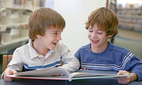 Two boy students reading together